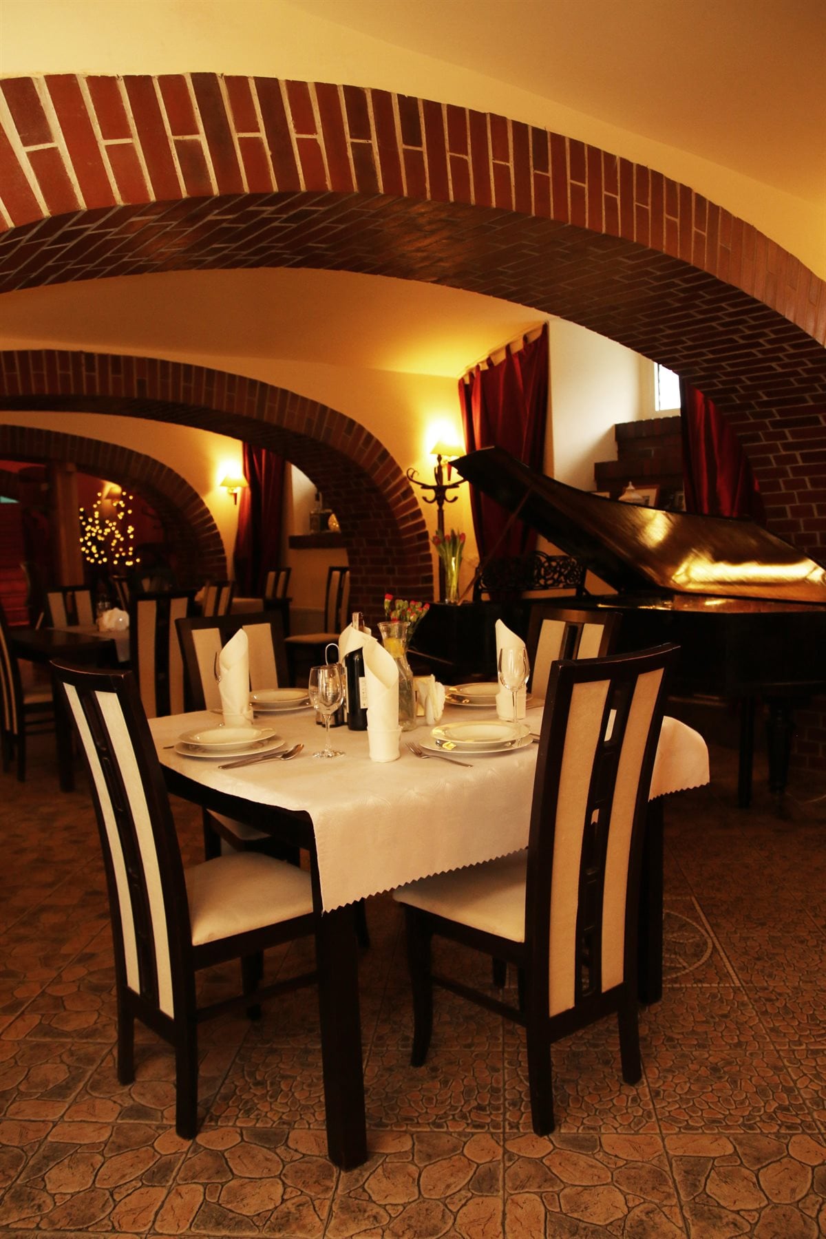 Nakryty stół i fortepian pod ceglanym sklepieniem restauracji Polonia